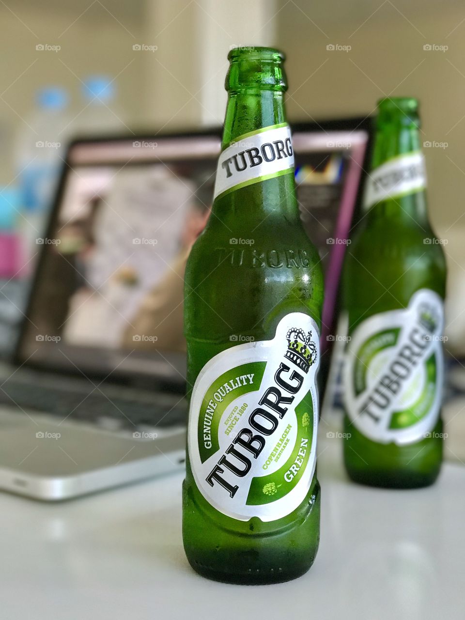 Green bottles of Tuborg beer from northern suburb of Copenhagen, Denmark, on working desk