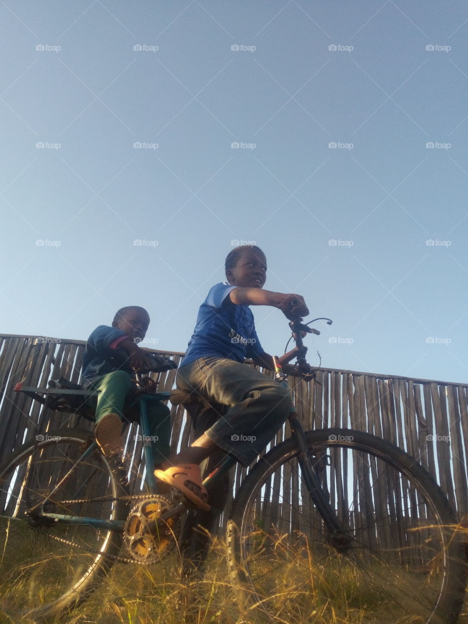 Two African boys riding on a bicycle.