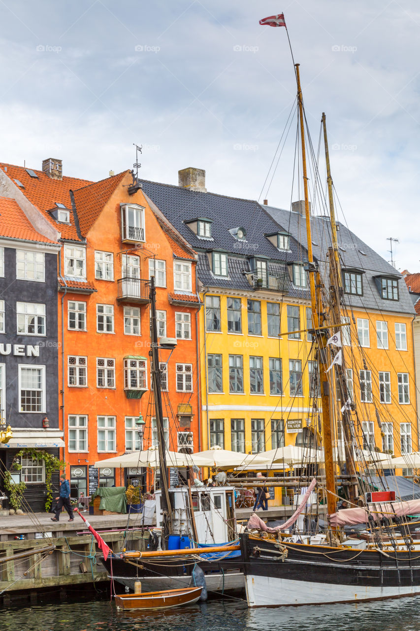 Nyhavn area in Copenhagen, Denmark. Colorful houses and sailboats. Nordic design. Touristic and famous spot. Water and cloudy sky. Restaurants next to the water