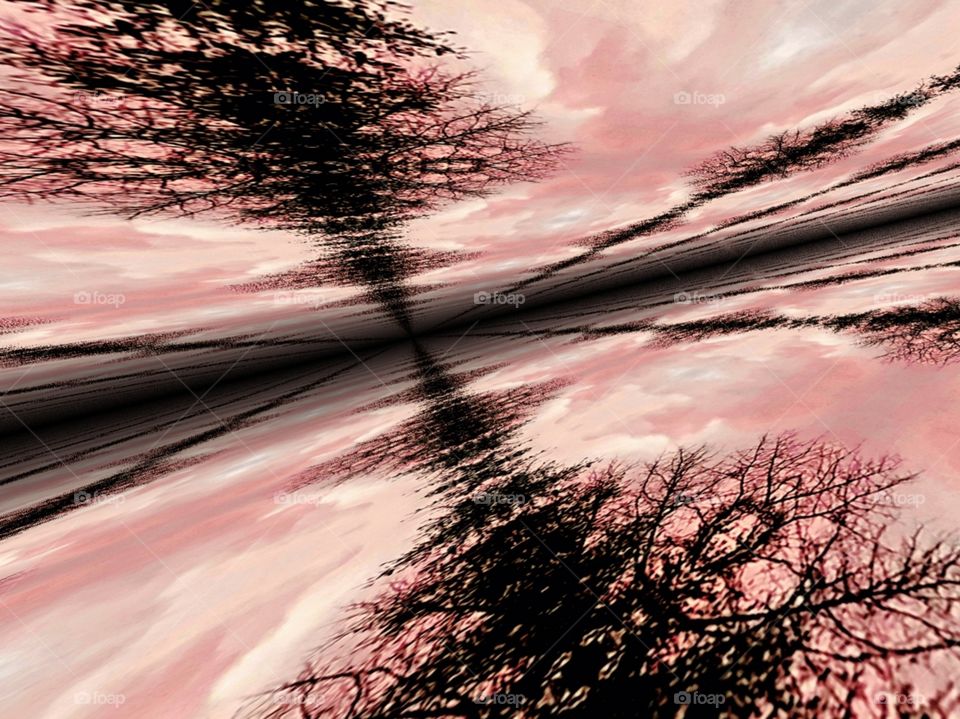 silhouette of landscape mirrored and distorted  pink cloudy sky at sunset