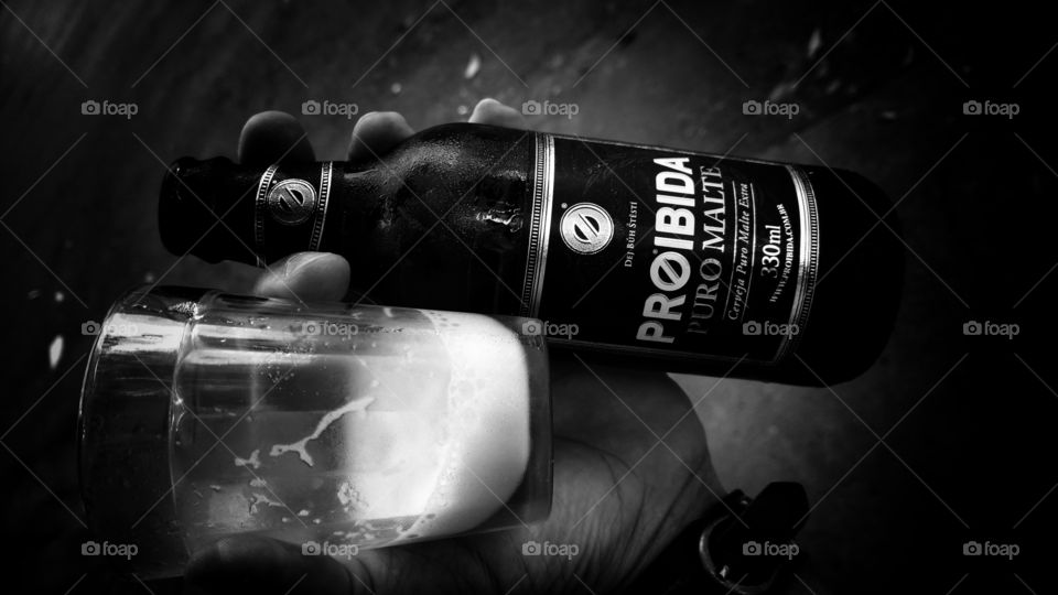 Black and White, garrafinha de cerveja Proibida Puro Malte, e um copo com espuma.