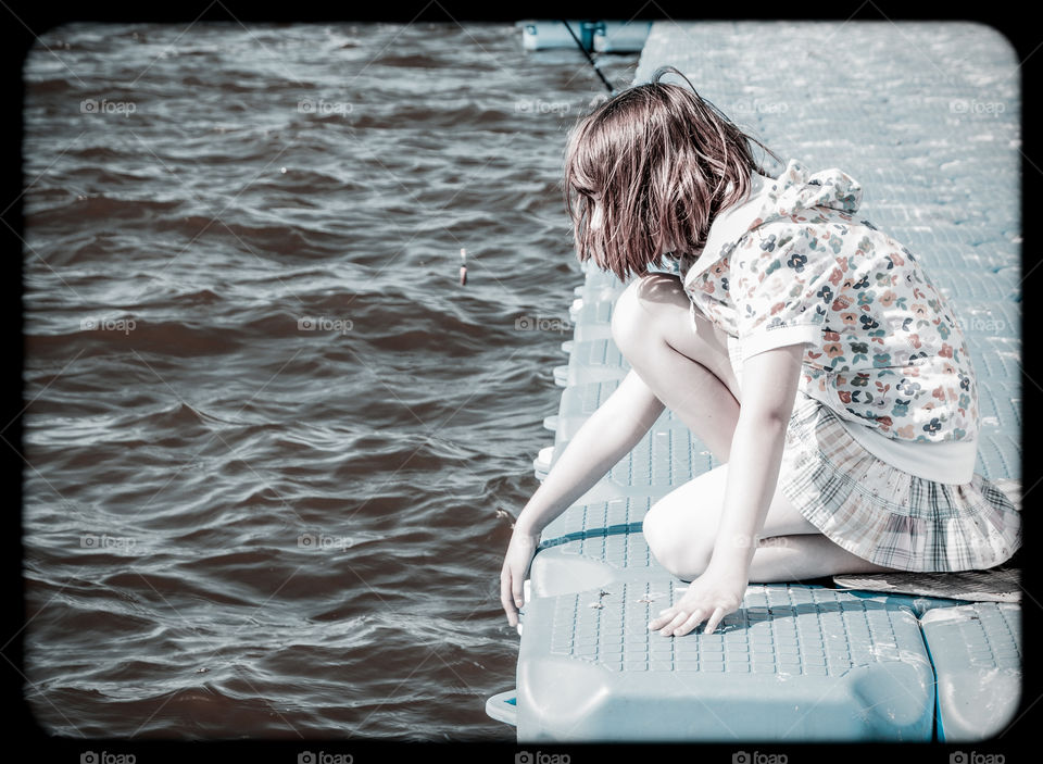 Young girl looking into a lake's watet