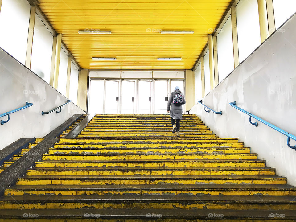 Walking upstairs with a backpack by the yellow steps 