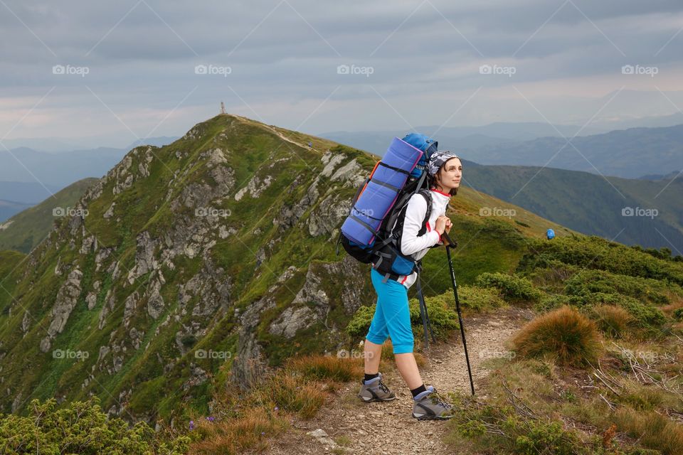 girl hiking with backpack in the mountains looks beyond the horizon
