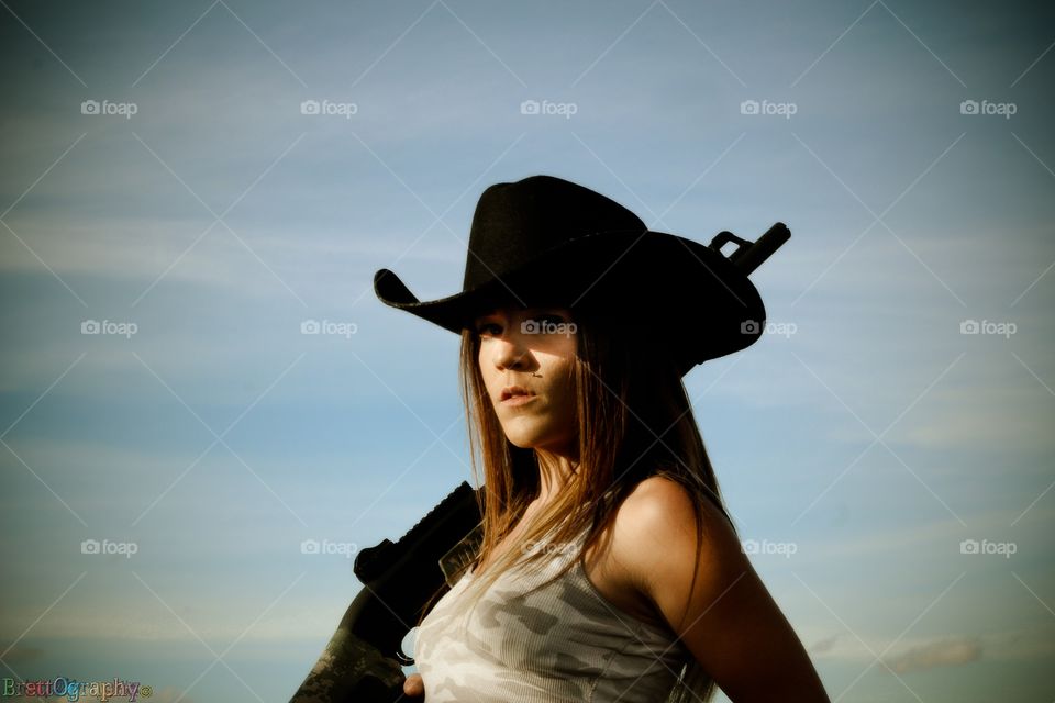 Close-up of a woman wearing hat holding riffle in hand