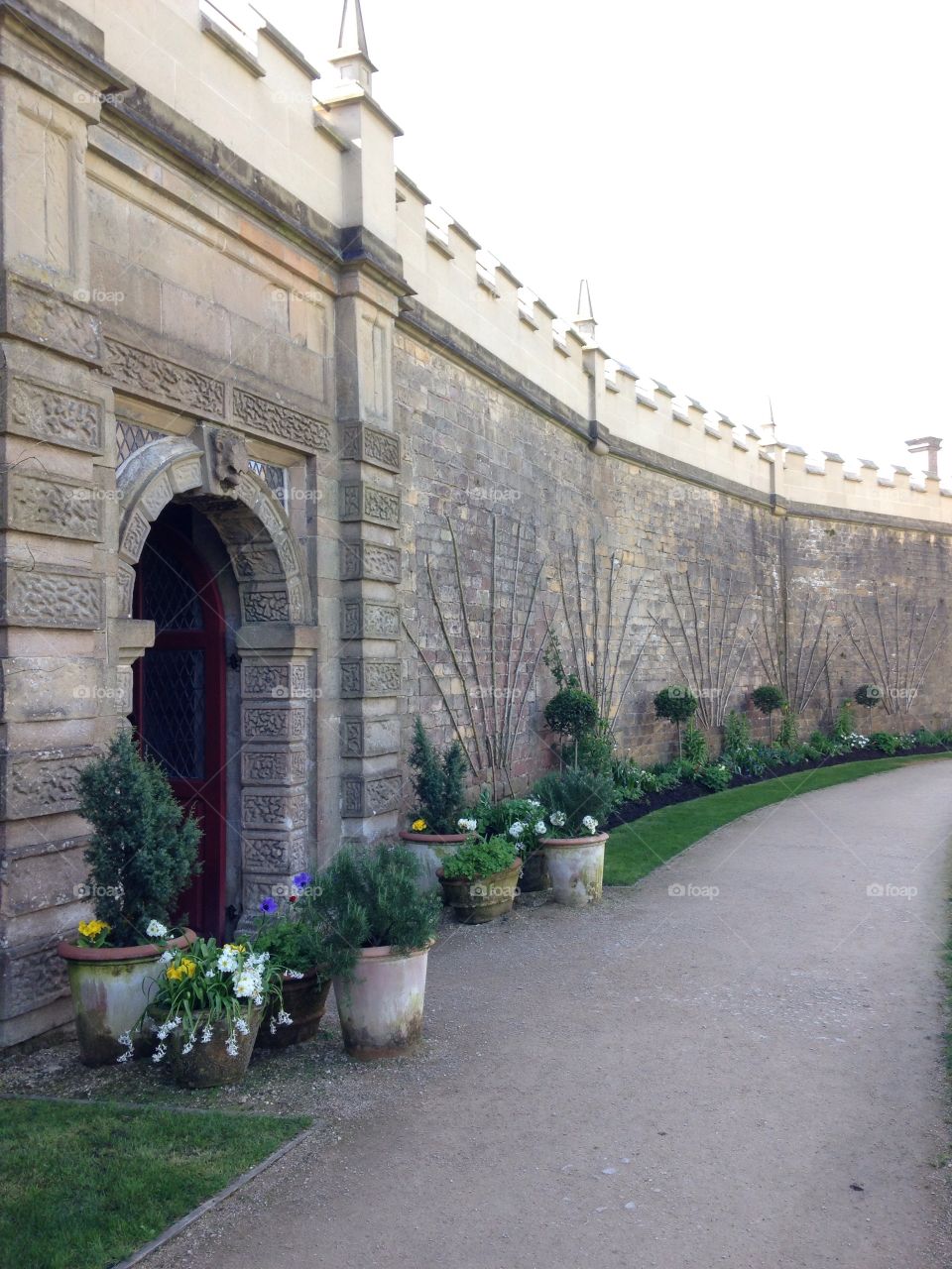 Battlement topped wall with plants and archway to garden at Bolsover Castle in Derbyshire
