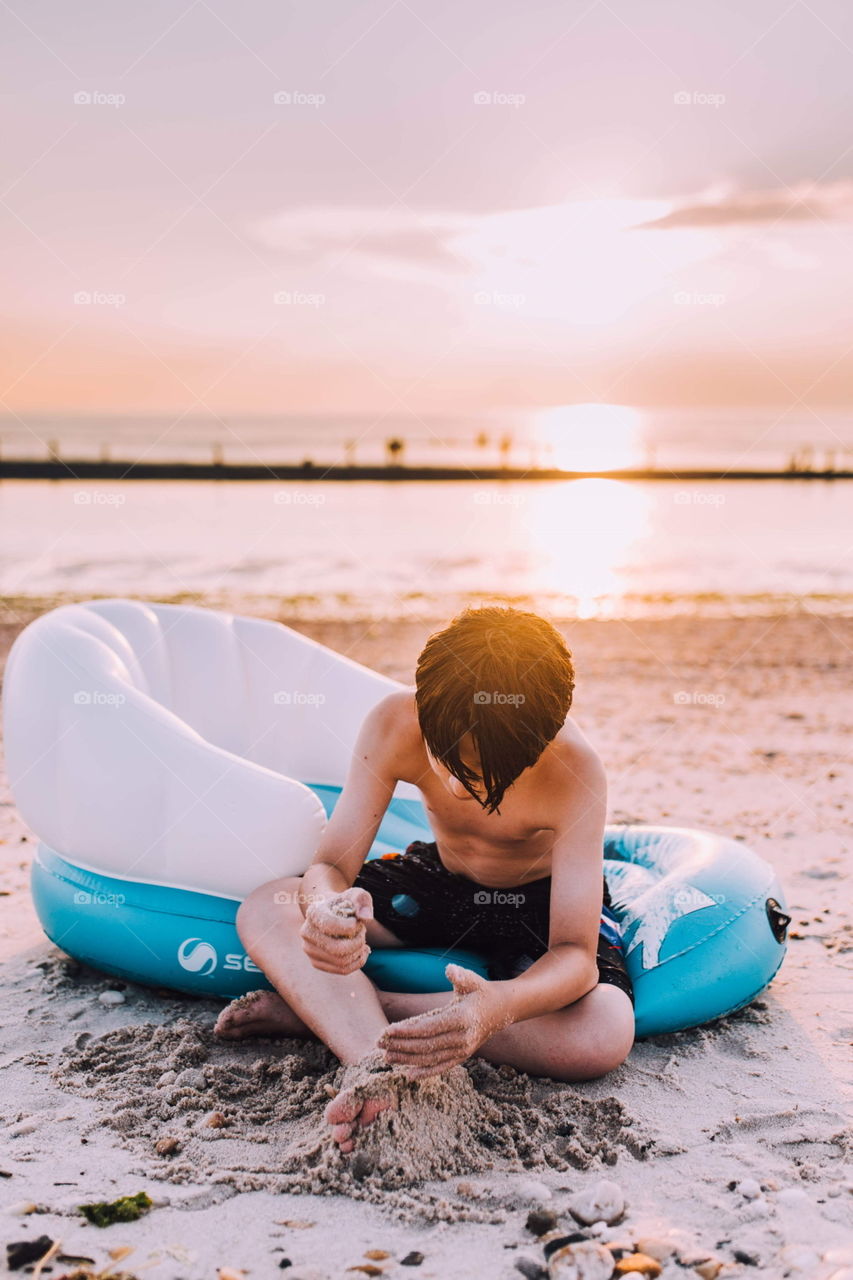 Young boy playing with sand on the beach 