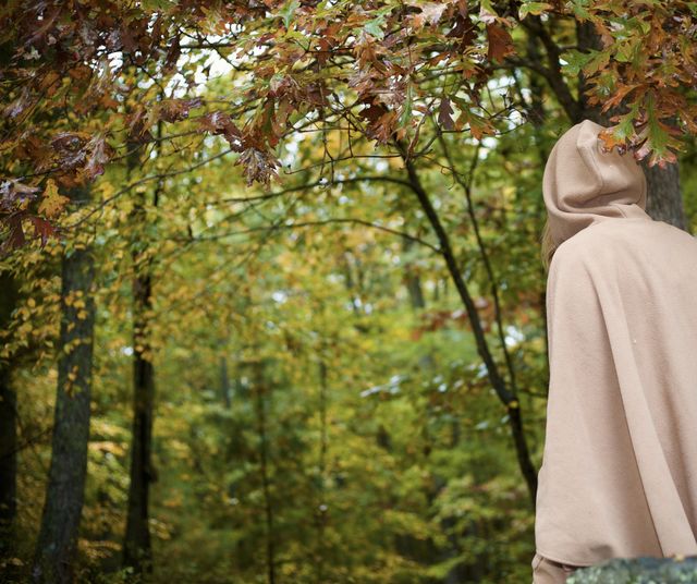 Rainy Fall Daze: Woman in Hooded Cloak walking among a Autumn wonderland and wet turning leaves