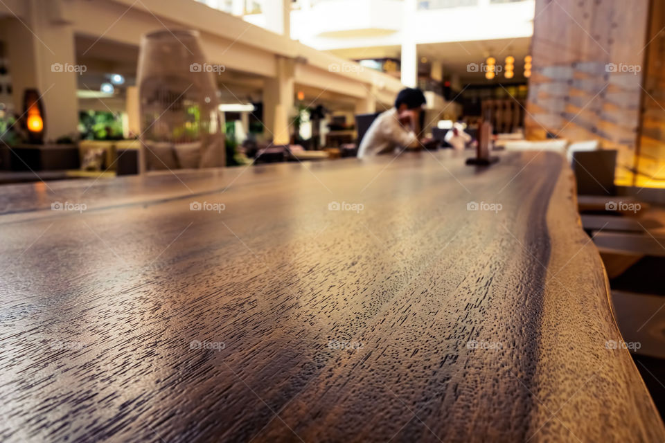 Waikiki, Honolulu, Hawaii, USA - December 15, 2015: Lounge area of the Waikiki Beach Marriott Resort and Spa Hotel. Public accesses this area frequently. Image features warm color and a person seated at a long wooden table reading. Image emphasizes on the textured table top.