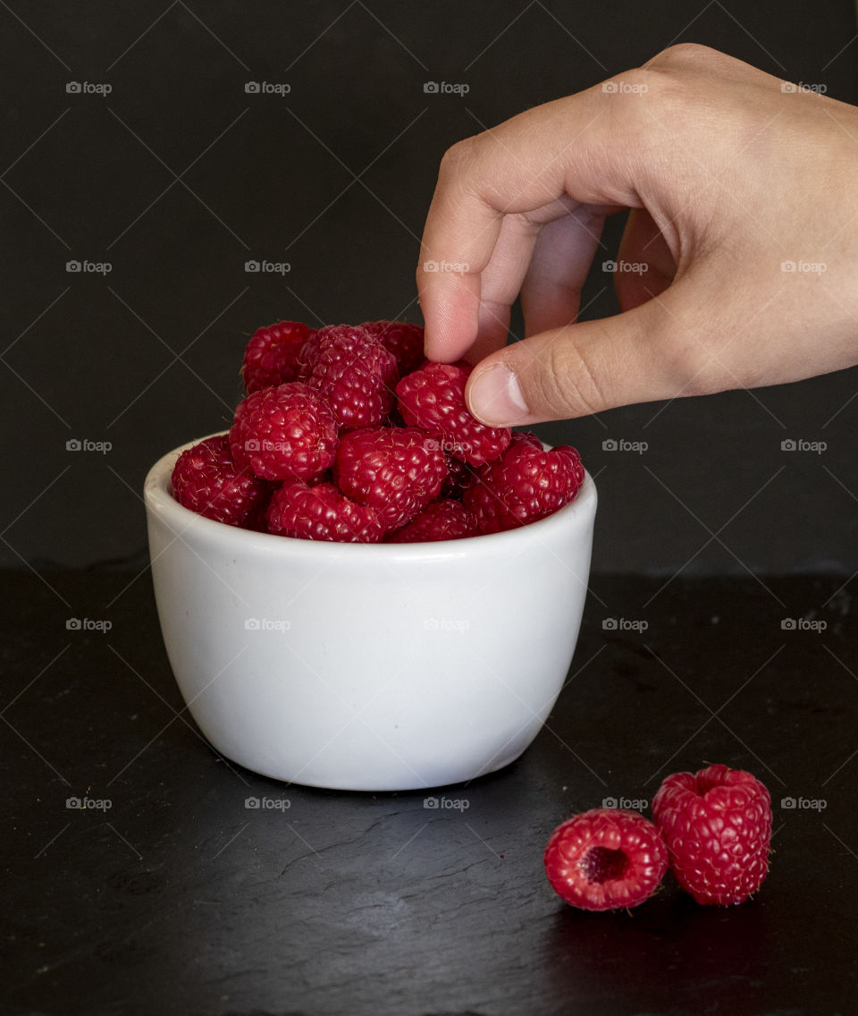 Picking a raspberry from a bowl