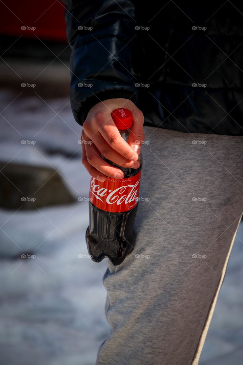 Coca-Cola bottle in a hand of a toung man