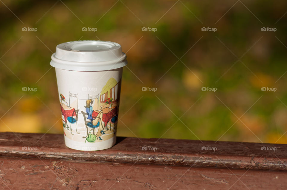 Cup of take away coffee on a bank in the park