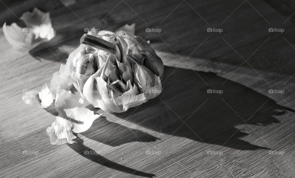 Bulb of garlic sitting on a cutting board by a window.