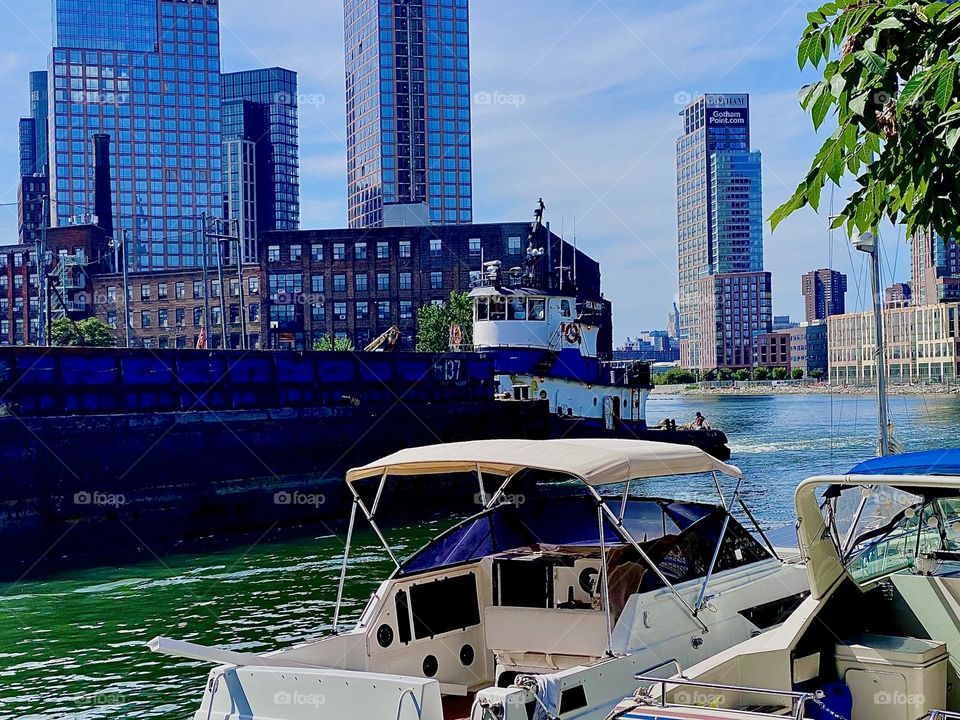 The rather long barge has begun to pass us by on the “East River” at “Newtown Creek” by the “Pulaski Bridge” in LIC, Queens. Across the water we can see “Greenpoint”, Brooklyn. 2023. Hypnotic Productions