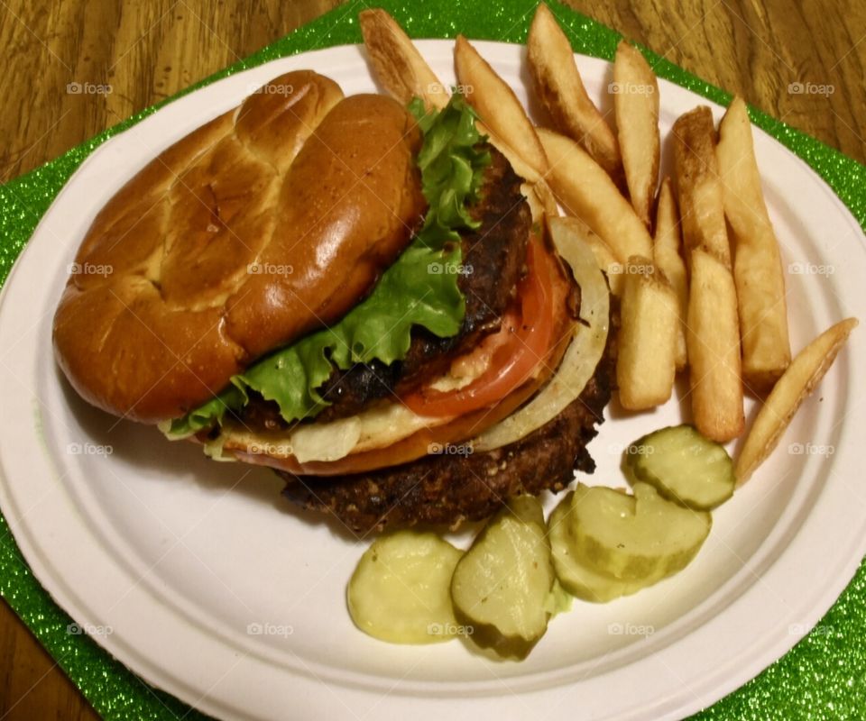 Cheeseburger and fries with pickles on the side