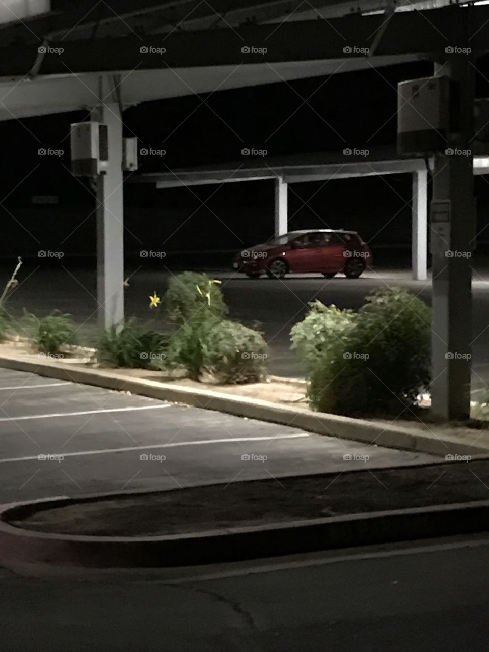 A red vehicle in an empty church parking lot on a quiet night.