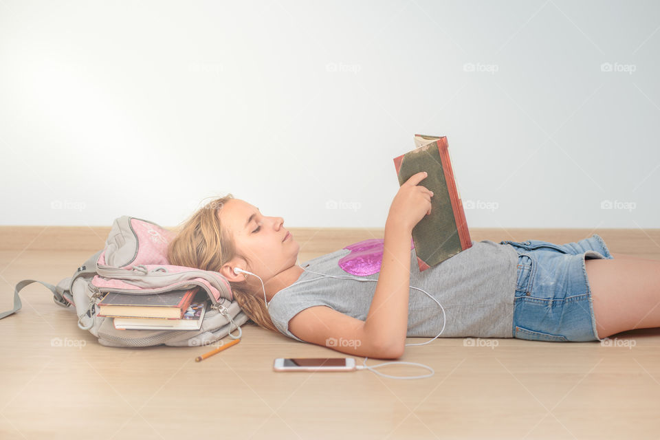 Teenage girl listening music and reading a book