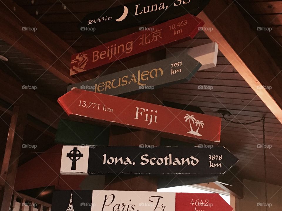 Direction travel signs with kilometre distance distance hanging in an Irish Pub in Iona, Cape Breton , NS, Canada. Where do you want to vacation? The moon, Beijing, Jerusalem, Fiji, Iona Scotland, Paris France. 