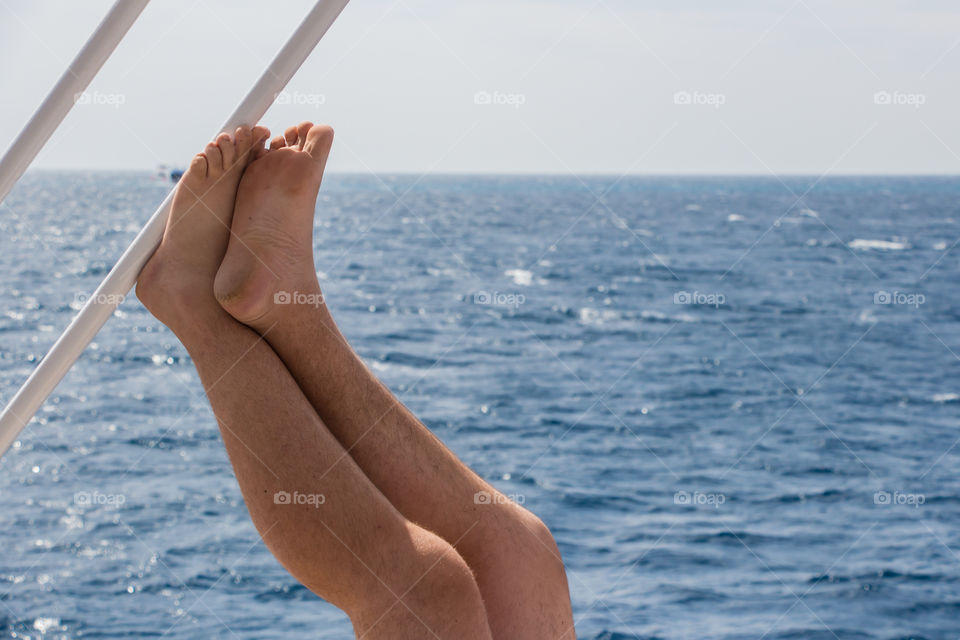 Everyone has his own idea of relaxation. A man hanging his leg up on a boat.