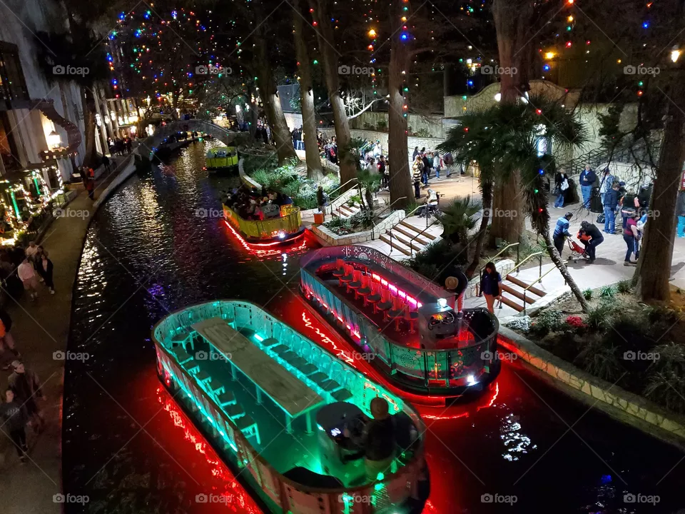 Riverwalk San Antonio decorated with Christmas lighting on the tourist river boats , the trees and hotel balconies.