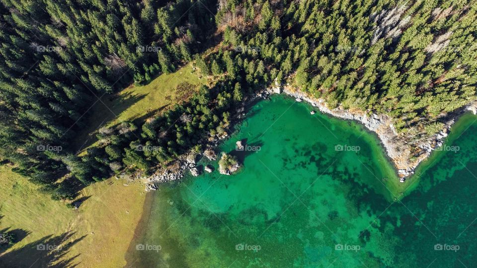 Aerial view of amazing green lake surrounded by pine tree forest