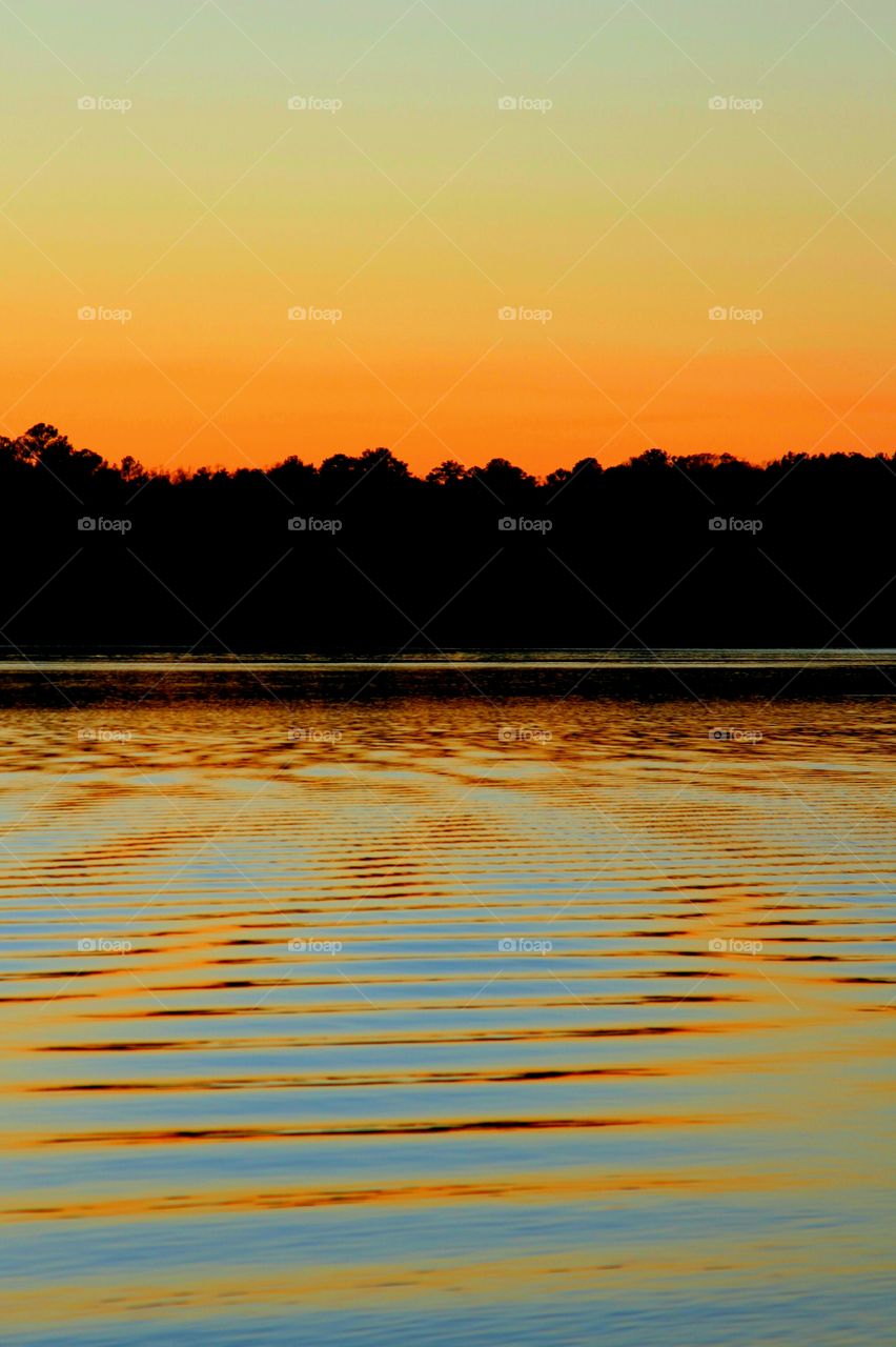 orange and blue reflected ripples during sunset on the lake.