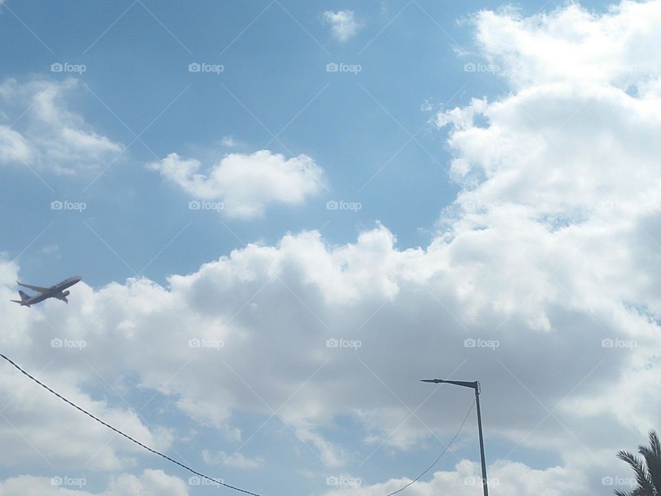 Electric lamp and beautiful flying airplane cross the sky.