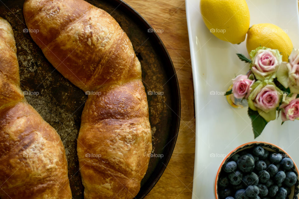 High angle view of freshly baked croissants on baking pan with bowl
Of blueberries and autumn roses 