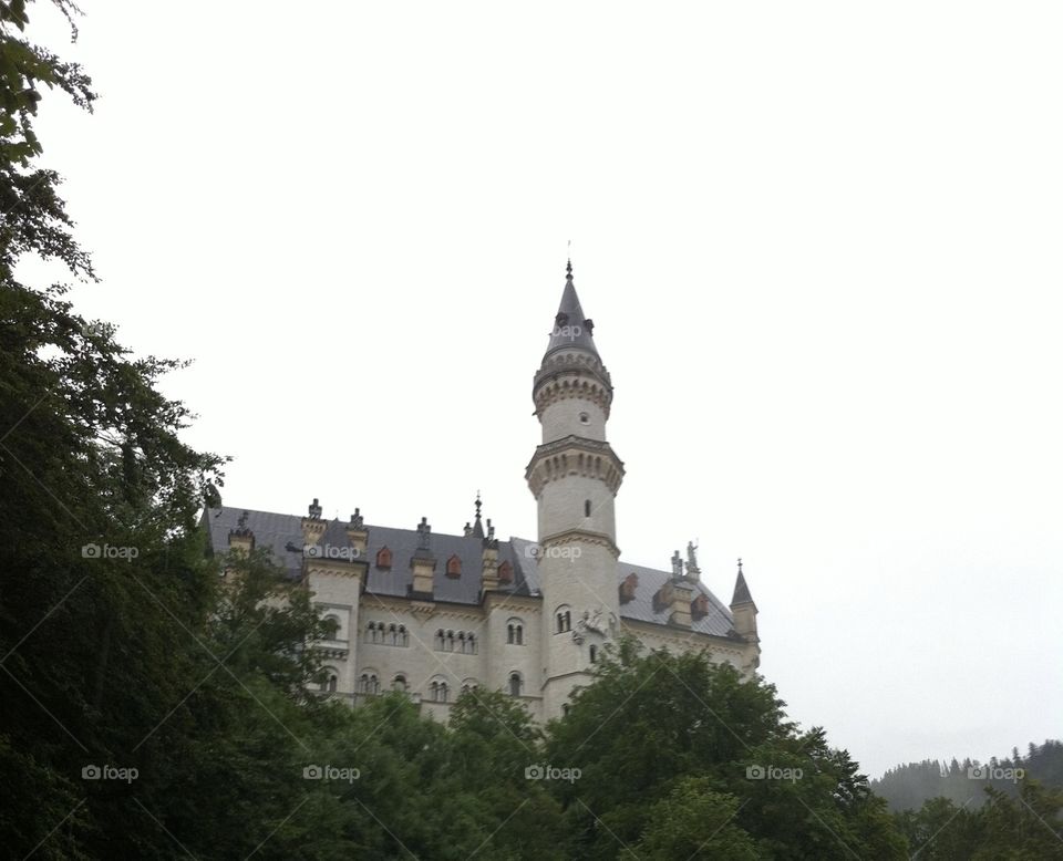 German castle spires above the trees. Overcast sky, fairytale setting, travel in southern Germany. 