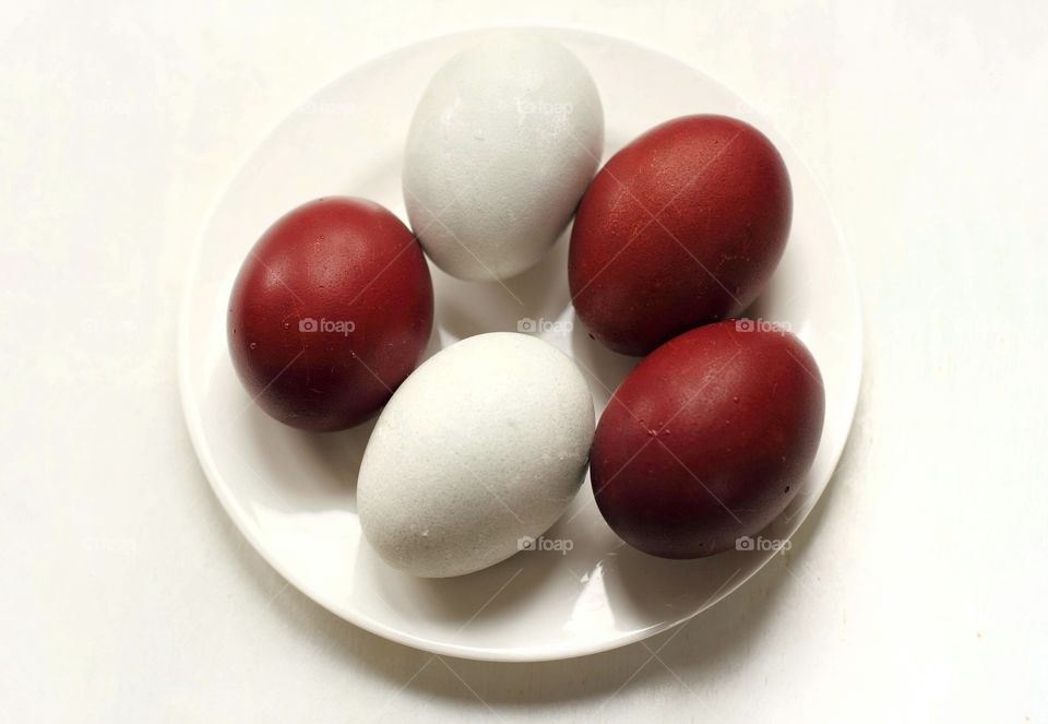 White and red easter eggs on a white saucer