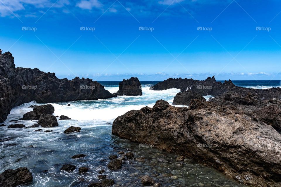 waves breaking against volcanic rocks