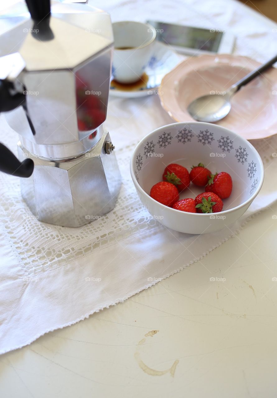 Strawberries and coffee. Table with stain of coffee, bowl with strawberries and coffeecup
