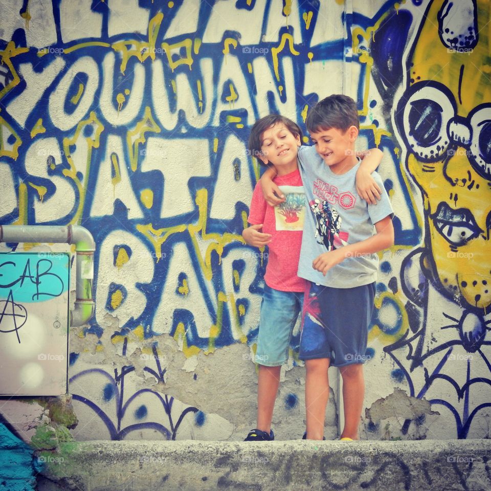 Two friends walking near the graffiti wall