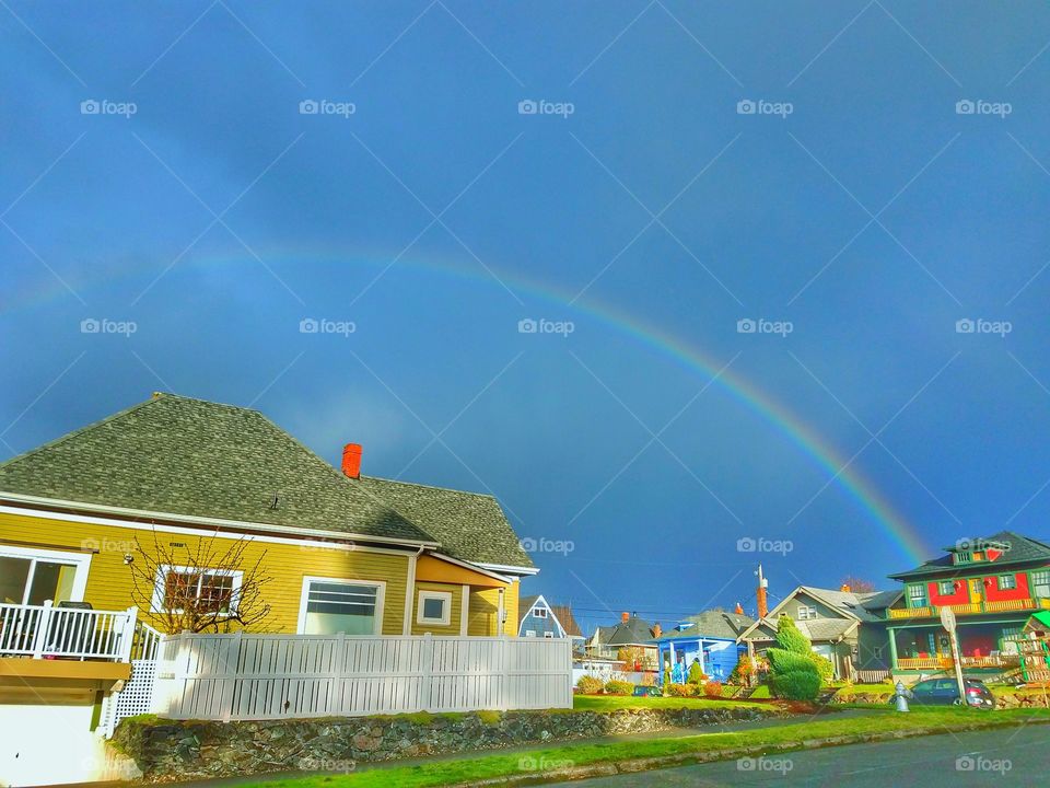 A rainbow shows over colorful homes after a storm.