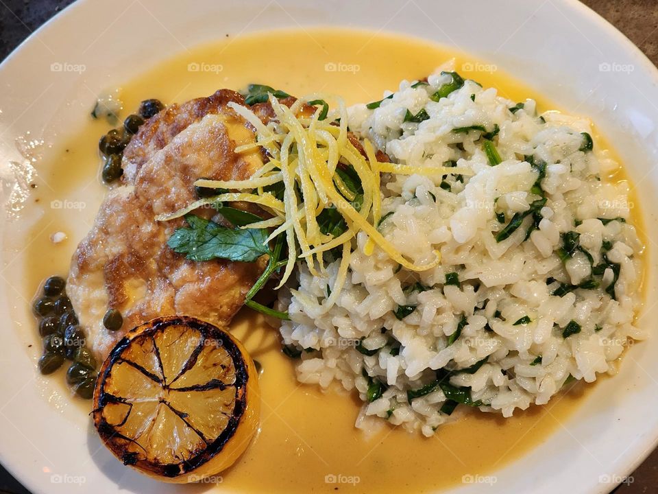 Lemon chicken breast, rice and beans with a slice lemon on a dinner plate.