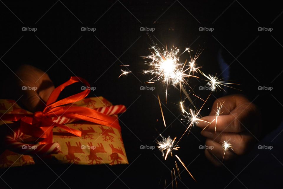 Christmas and New year holiday gift in the female hand and Bengal lights