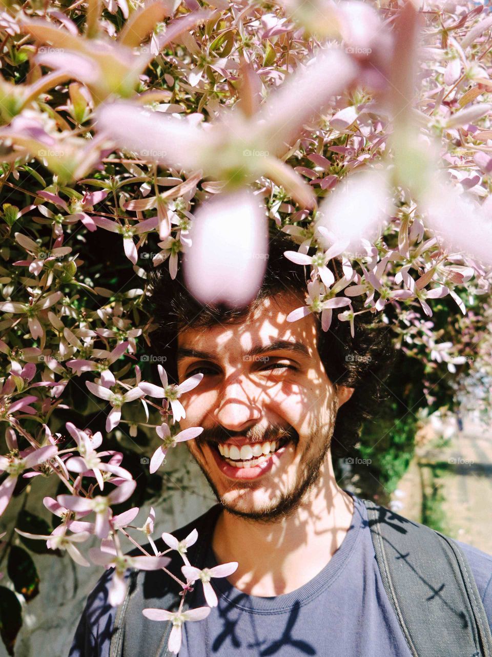 Beautiful Man with mustache and beard, with pink flowers ln his head, creating a nice shadow. This is a beautiful portrait.