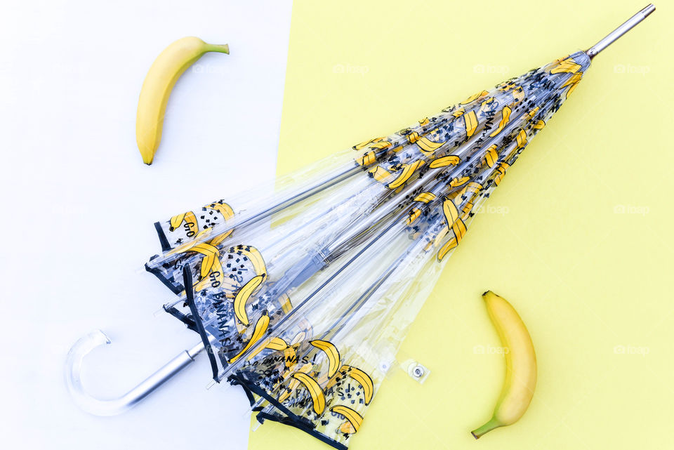 Flat lay of a banana print umbrella on a yellow surface next to bananas