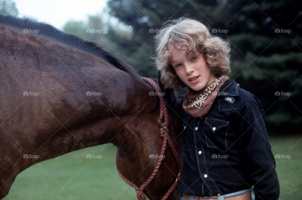 Young boy stands by his horse in the field