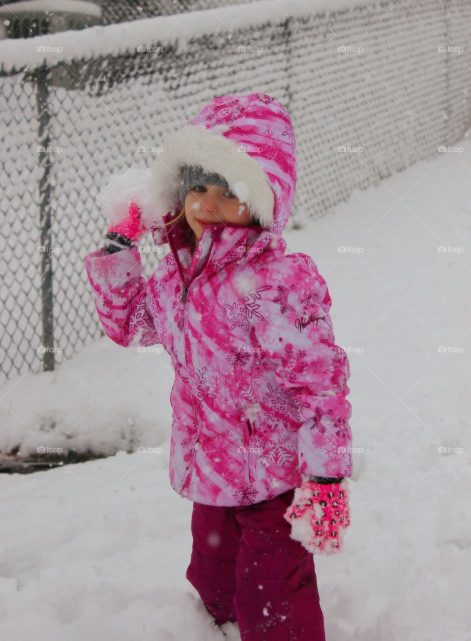 Cute little girl holding snowball in hand