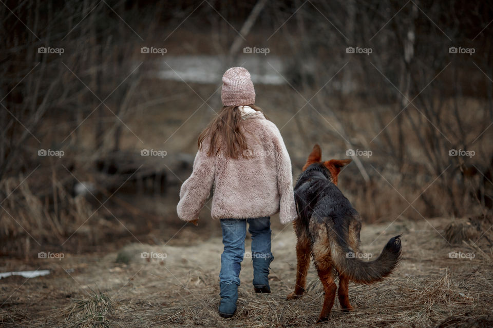 Little girl with German shepherd young male dog walking outdoor at spring day