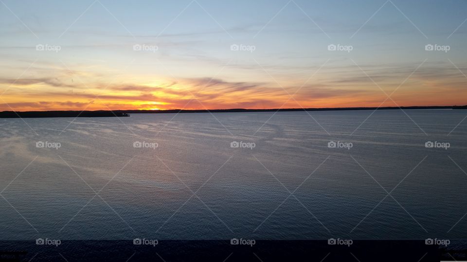 sunset on a lake etched with the passage of boats