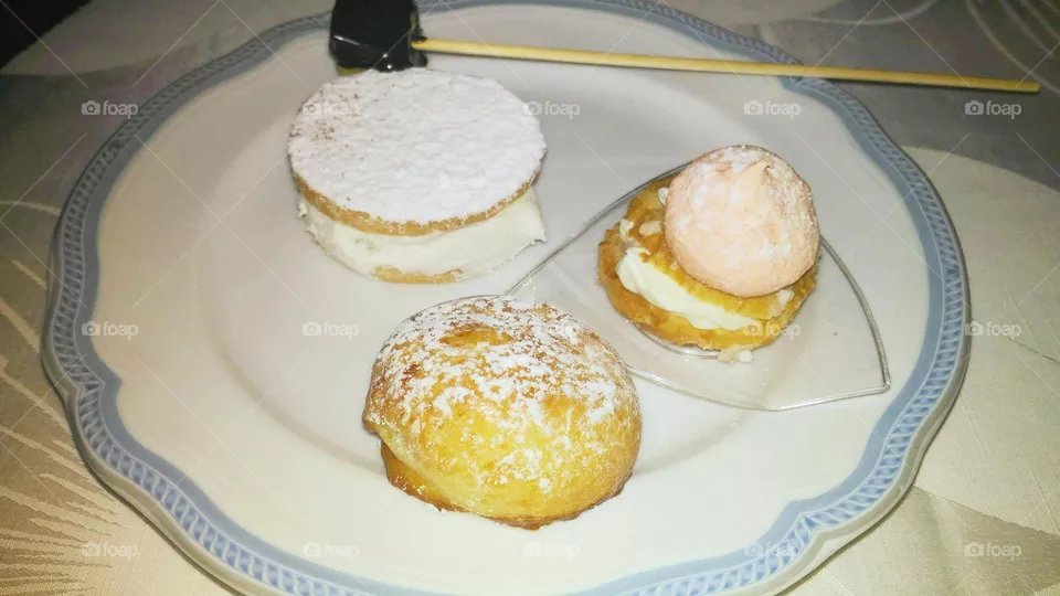A set of Neapolitan pastries (Sfogliatella liscia, deliziosa ) served with a white and blue dessert plate and a stick for skewering sweets