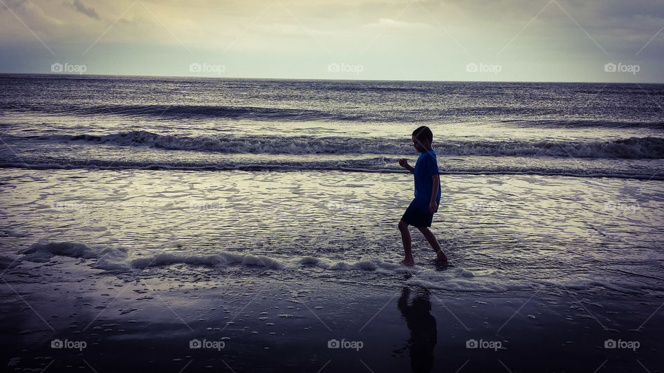 Edisto Beach fun. A young man splashing in the waves at Edisto Beach in the spring.