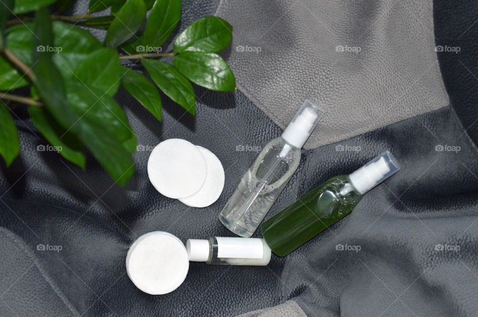 Jars with cream, shampoo and cosmetics on a background with green plants