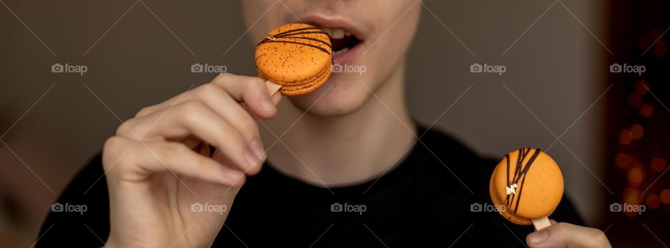 Selective focus to orange macarons in hand of person who going to eat it.