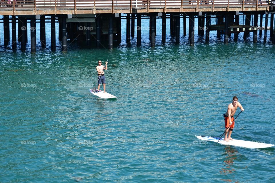 Two guys paddle boarding