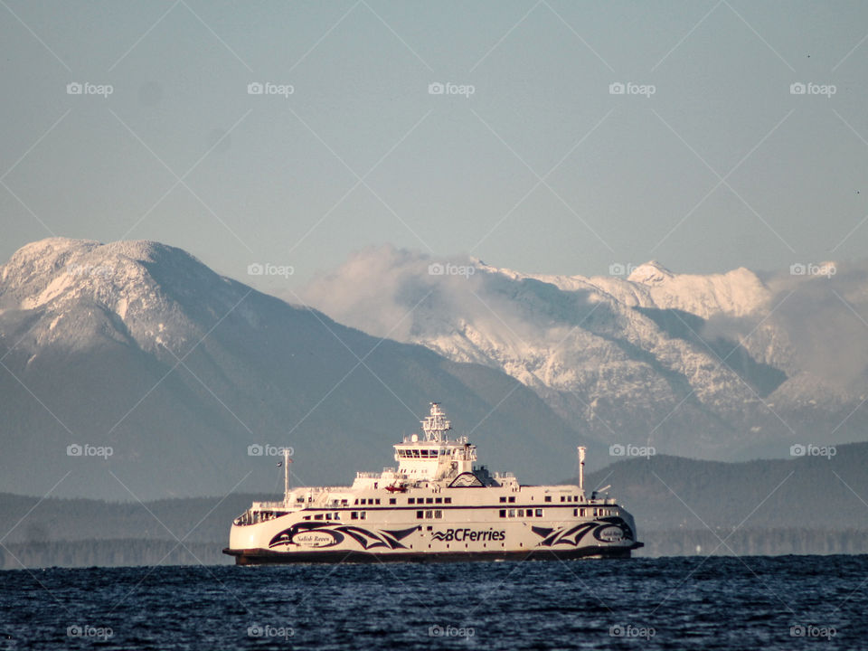 A ferry crossing between the island & the mainland. Wispy clouds danced amongst the peaks as the setting winter sun kissed the snow covered mountains & the ferry glowed golden on the deep indigo waters. 