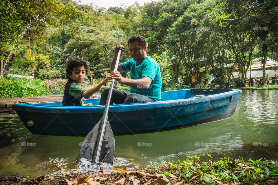 Father and son enjoying time together in summer inside a boat on the lake