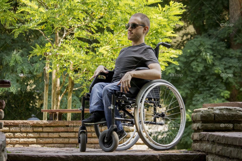 Young blind man in a wheelchair rests in the park